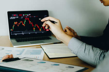 Two investors working together are analyzing the stock chart on the computer screen at the company.