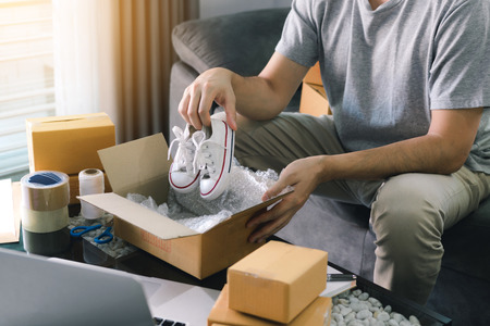 Asian entrepreneur teenager is carrying baby shoes and put in a cardboard box customer to deliver...