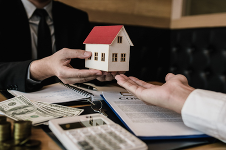 Real estate agent congratulations to new buyer by giving house model to client in the agency office.の写真素材