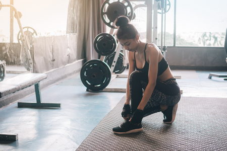 Woman sitting with hands lacing up sneakers shoes with copy space.の写真素材
