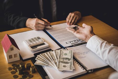 Salesman house brokers provide key to new homeowners in office.