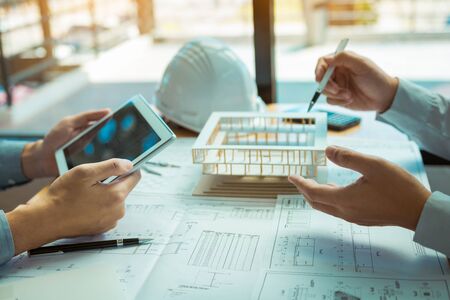 Two engineering working together and using digital tablet looking blueprint and analysis with...