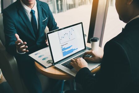 Two businessmen are talking about the results of operations in the company financial statements on...