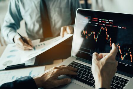 Investors are pointing to laptops that have investment information stock markets and partners taking notes and analyzing performance data.の写真素材