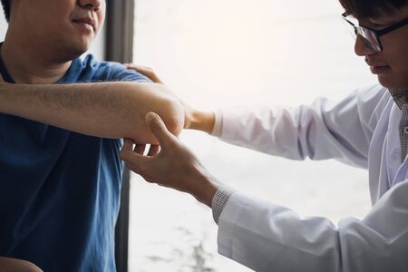 Physical therapists are checking patients elbows at the clinic office room.の写真素材