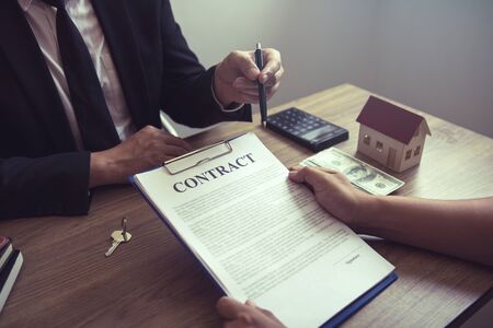 Home agents talking to home buyers who are signing contracts at the office.の写真素材