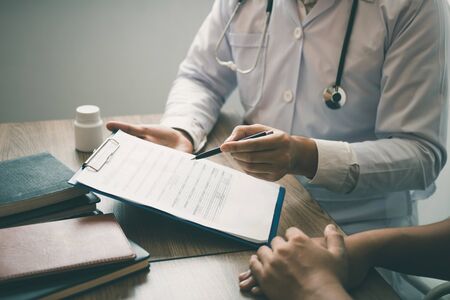 Doctor is writing the appointment letter to the patient at the clinic.の写真素材