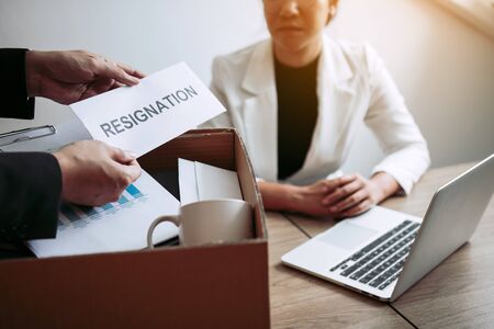 Male employee takes the handle to the resignation envelope while being handed over to the female manager.の写真素材