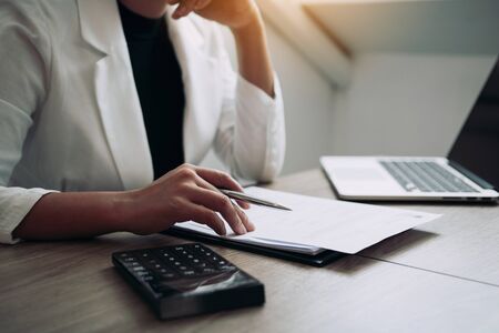 Women are sitting analyzing the company's financial statement plan using a calculator on his desk.の写真素材