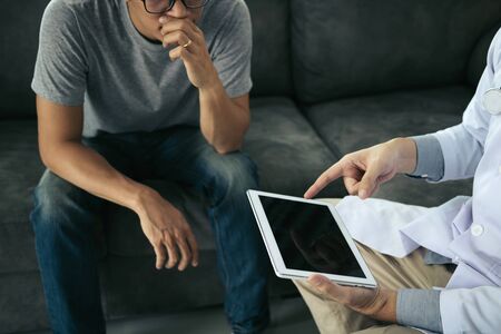 Asian patient was intensely listening while the doctor informed the results of treatment at his home.の写真素材