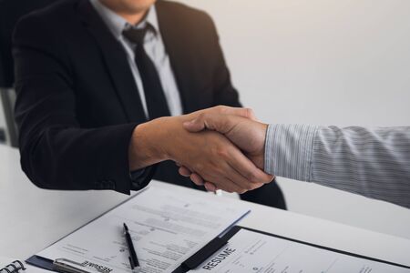 Manager and employee interview concept with handshake after talking about contract signing.