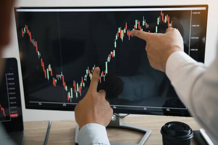 Two partnership investors discussion working together are analyzing the stock chart on the computer screen at the office company.の写真素材