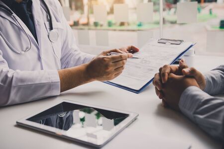 Doctor is writing the appointment letter to the patient at the clinic.の写真素材
