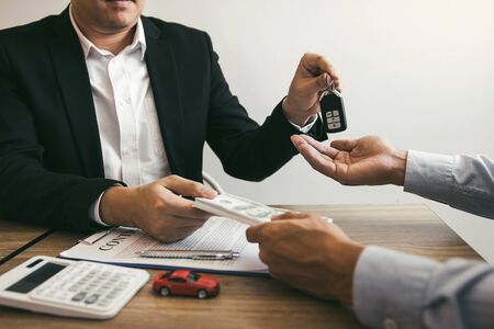 New car buyers and car sales agent people are exchanging by giving cash and new car keys to each...