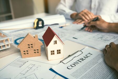 Architect working on blueprint discussing new project with colleague in office.の写真素材