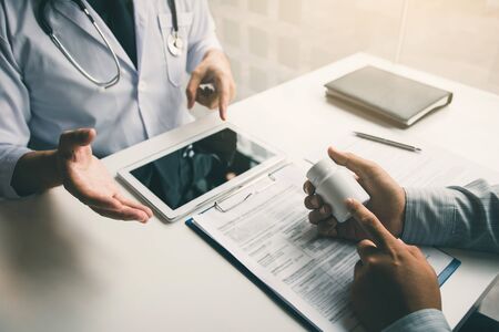 Asian doctor talking the patient at clinic while using the tablet explaining the patient condition and the treatment result.の写真素材