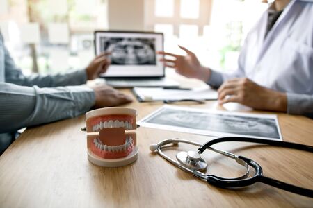 Dentists are discussing dental problems at report x-ray image on laptop screen to patients.の写真素材