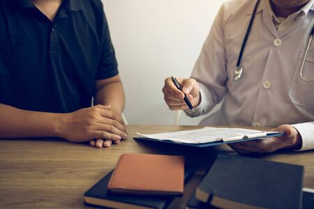 Doctor is writing the appointment letter to the patient at the clinic.の写真素材