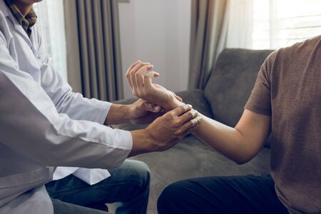 Physical therapist checks the patient wrist by pressing the wrist bone in clinic room.