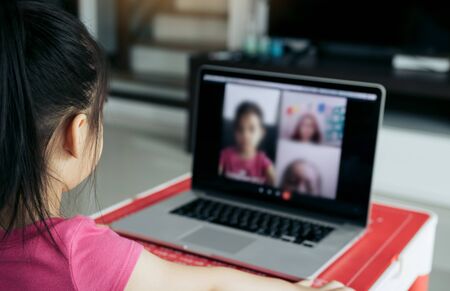 Little asian girl attending to online e-learning platform class from home while school has been...