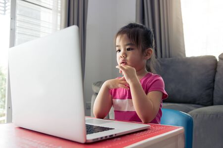 Kindergarten students are learning online with teachers and friends chatting on video on a computer...