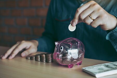 Men are holding coins dropping to the piggy bank with the concept of saving.