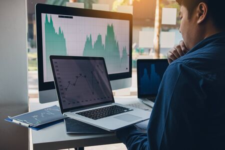 Investors are using laptops entering investment websites stocks market and partners are taking notes...