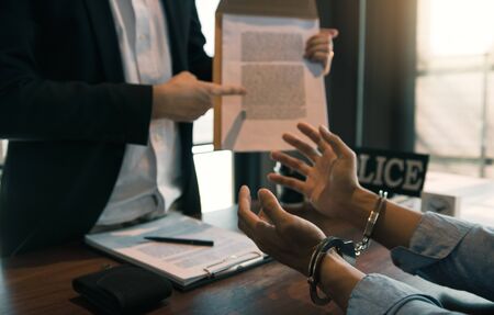The police officer pointed to the document requesting the arrest of the accused and handcuffed.の写真素材