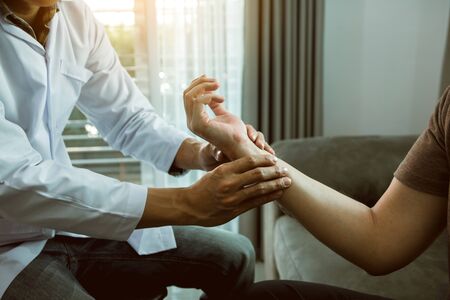Physical therapist checks the patient wrist by pressing the wrist bone in clinic room.の写真素材