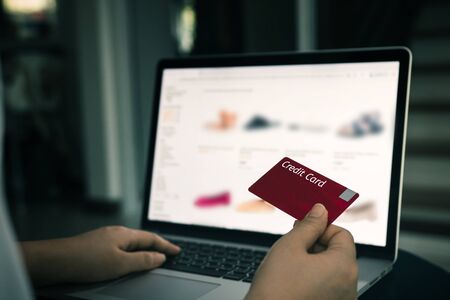 Online shopping concept with woman hand using laptop and looking credit card for purchase order product at home.の写真素材