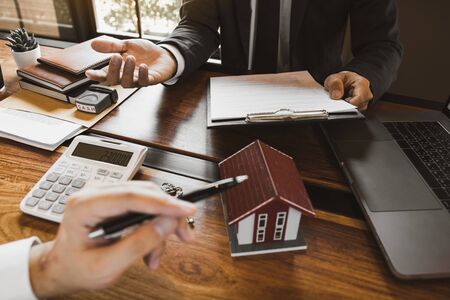 Business people home sales broker is using a pen pointing to the house model and describing the various components of the house.の写真素材