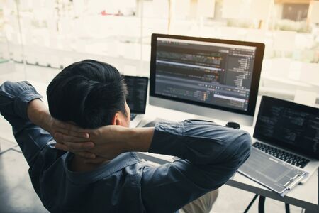 Asian programmers man are relaxing and looking at the code on the computer screen in the office.の写真素材