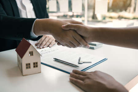 Home sales agents and buyers work on signing new homes and shaking hands.