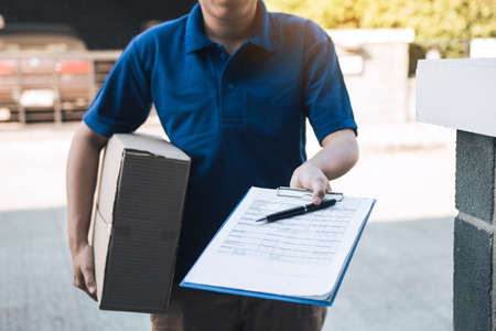 Young asian man smiling while delivering a cardboard box to the woman holding document to signing...
