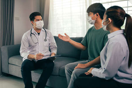 Asian couple is talking to a doctor about having a baby during an epidemic, as well as asking for advice on how to prevent the disease during the epidemic.の写真素材