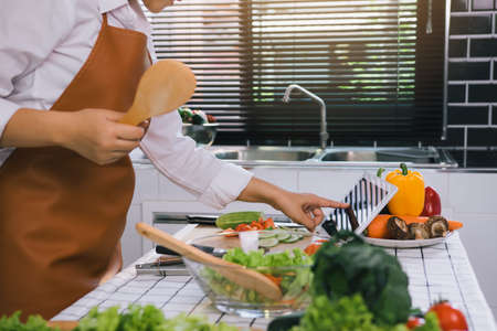 Asian women are using tablets to find recipes from cooking websites at the table.の写真素材