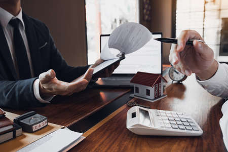 Business people home sales broker is using a pen pointing to the house model and describing the various components of the house.の写真素材