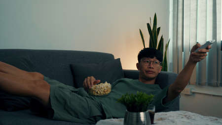 Asian guy is relaxing for the weekend by watching series his home at night.の写真素材