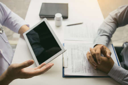 Asian doctor talking the patient at clinic while using the tablet explaining the patient condition...