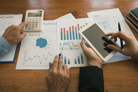 Two businessmen are working analyzing the company annual budget and using digital tablet to find...