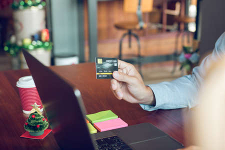 Asian man holding credit card and typing keyboard on laptop with shopping online.
