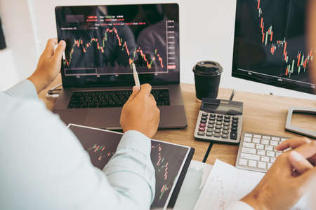 Two partnership investors discussion working together are analyzing the stock chart on the computer...