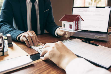 Investors are using st pen on the contract paper about buying a new home while filing cash as a deposit for the agent.の写真素材