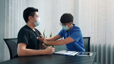 Asian doctor is using a stethoscope listen to the heartbeat of the patient.