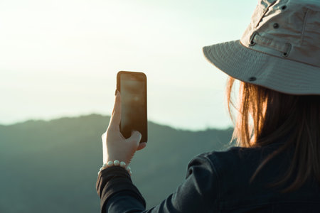 Asian female tourists use their mobile phones to take pictures of the scenery at the top of a fresh...