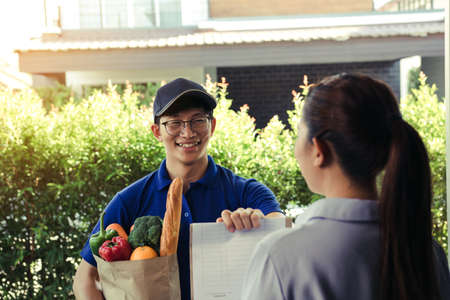 Supermarket food delivery staff deliver bags to female customers in front of the house.