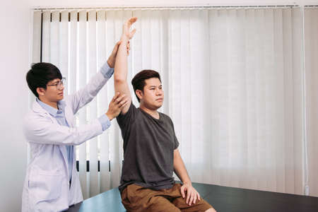 Chiropractor stretching a young man arm in medical officeの写真素材