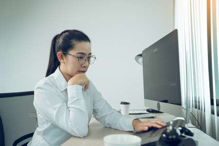 Asian female software developer is worried about analyzing code-based systems at his office.