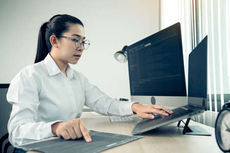 Software developers are analyzing about the code written into the program on the computer in office room.の写真素材