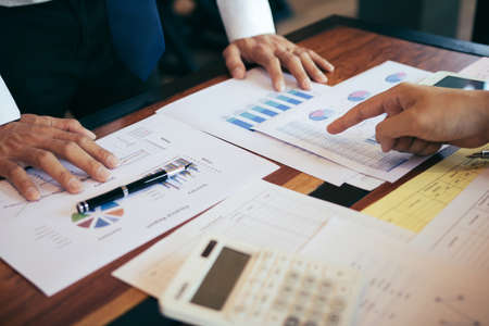 Business people pointing on statistic number result and analysis finance cost with checking summary...